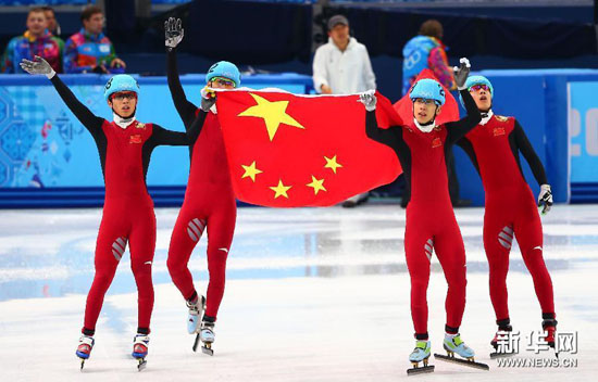 图为2月21日,在2014索契冬奥会短道速滑男子5000米接力比赛后,中国队队员手举国旗庆祝。新华社记者龚兵摄 短道男子5000米接力决赛出发后的第一个弯道发生了碰撞,中国队第一棒武大靖和一名荷兰选手摔倒后滑出赛道,但是中国队没有放弃比赛,继续赶超对手获得铜牌,追平冬奥会历史上的最好成绩。