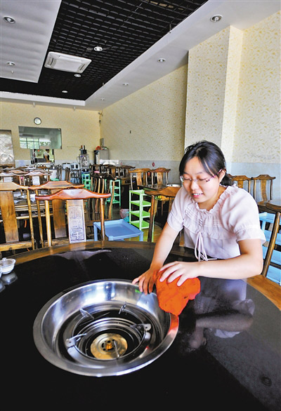 昨日,南岸弹子石,李密在自己的火锅店内收拾餐桌。