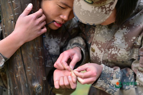 10月17日,女兵蒙裴菲(左)手掌扎进了木刺,战友为她拔出木刺.