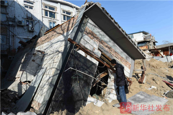 1月28日，一名工作人员在北京市德内大街93号院塌陷现场观看倒塌的建筑。新华社发布客户端记者罗晓光摄