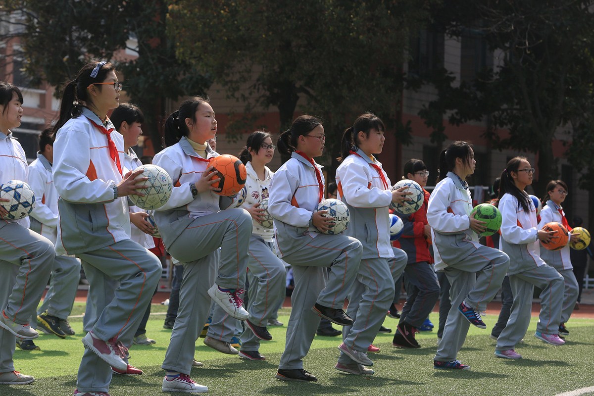 3月25日,杭州启航中学的学生抱着足球在体育课上跳操热身,这套将