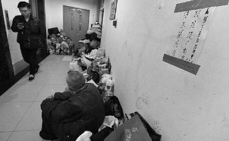 堆积的杂物占据了一半楼道，老人经常坐在其中吃饭、休息