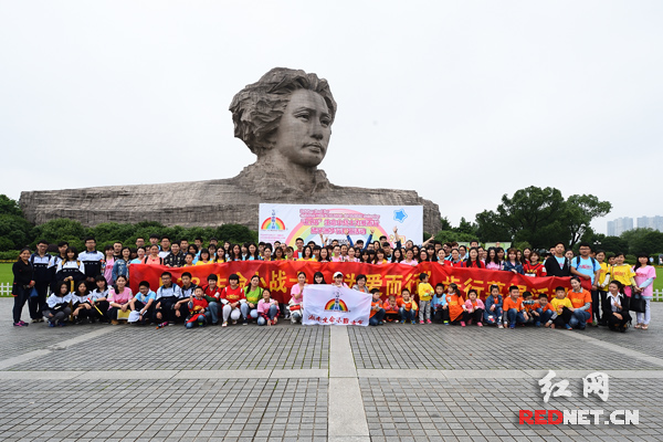 志愿者在橘子洲毛泽东青年艺术雕像前合影。
