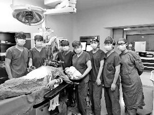 浙江大学医学院附属妇产科医院参与手术的团队成员与新生儿和61岁的张女士合影。新华社发