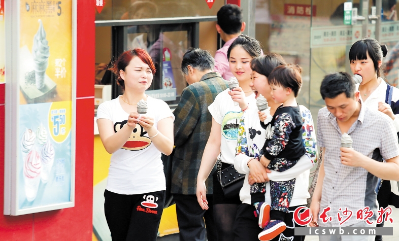 炎炎夏日，高温难耐，五一大道上，几位市民人手一支冰激凌，驱赶高温的炙烤。长沙晚报记者 余劭劼 摄