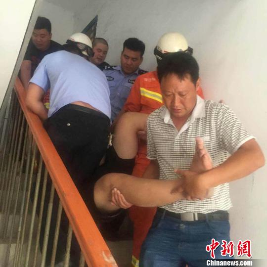 消防队员及民警将150公斤的“胖男”抬下楼。 警方供图 摄
