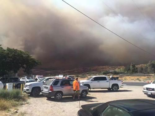 从拉斯维加斯回洛杉矶的中国游客在15号公路附近休息站休息，看得见浓烟蔽日。(美国《世界日报》)