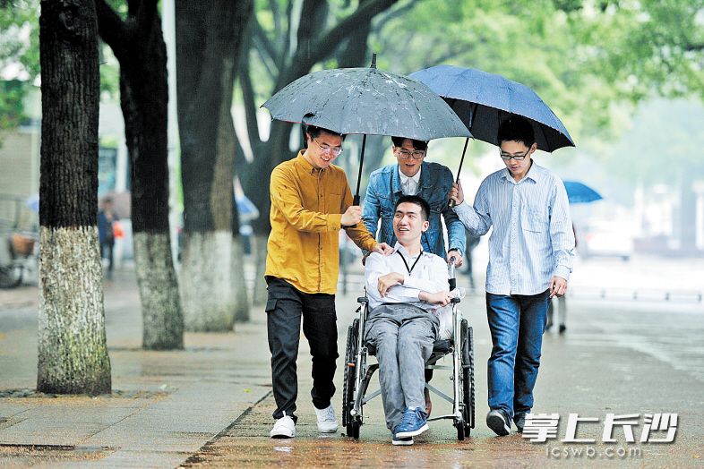 昨日下午，中南大学软件学院校区内，同学们推着莫天池（中）在校园内行走。7年来，莫天池在大家的温暖关爱下，不忘初心，始终保持昂扬的学习劲头。 长沙晚报记者 王志伟 摄