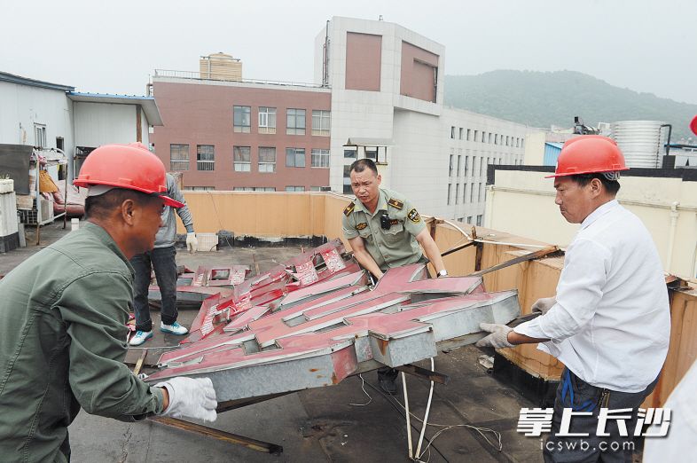 昨日下午，在岳麓区阜埠河路，城管执法人员正在拆除一酒店楼顶发光字。 长沙晚报记者 余劭劼 摄
