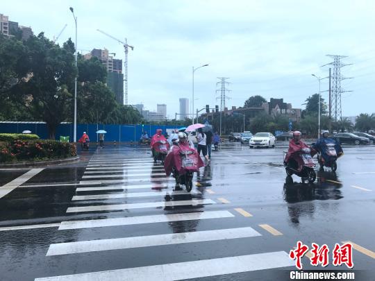 海口23日上午维持阵雨天气，市民穿戴雨具出行。 王子谦 摄