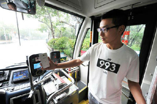 资料图片：7月2日，乘客在青岛交运31路公交车上使用手机支付公交车费。新华社发