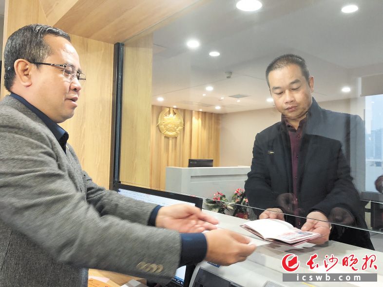 昨日上午，老挝驻长沙总领事馆领事习通·维莱哈（左）为罗富民办理了第一张签证。长沙晚报记者 朱敏 摄