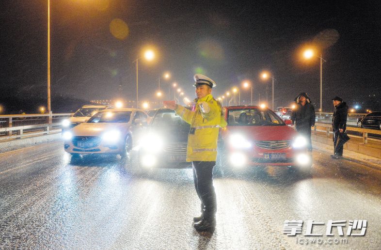 昨晚，由于低温降雪天气影响，三汊矶大桥桥面结冰，开福区交警在现场疏导交通。长沙晚报记者邹麟 摄