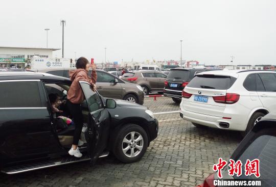 2月23日，海南海口新海港内，一位旅客拿出手机拍摄大批待渡车辆。 尹海明 摄