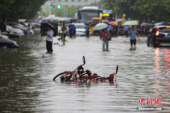 9月25日，南京城东银城东苑门口的道路上，市民在积水中涉水而行。持续的暴雨导致南京城不少路段严重积水，给市民的出行造成极大的影响。泱波 摄