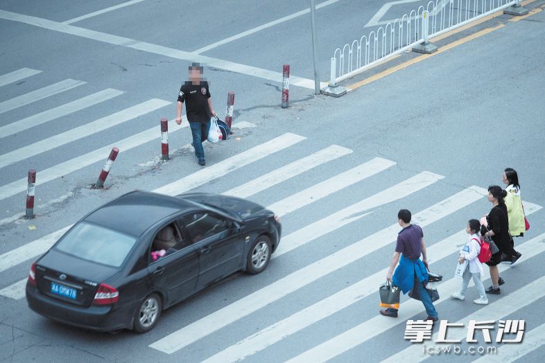 昨日晚高峰时段，晚报大道南湖大市场路段，一辆黑色小车从行人中穿过，疾驰而去。长沙晚报记者 黄启晴 摄