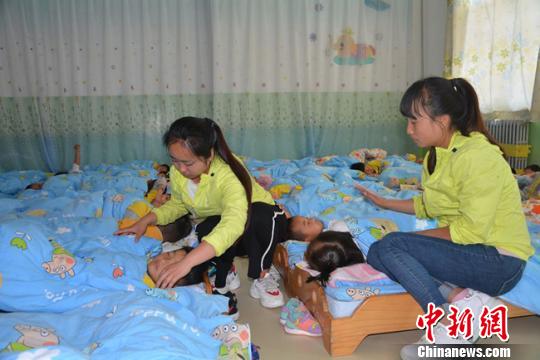 图为幼儿园老师照顾学生午休。 郭红 摄