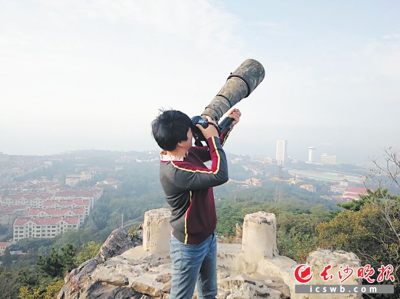 ↓攀登到山顶，肖辉跃在拍摄迁徙的候鸟。