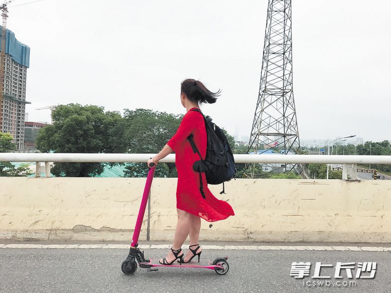 ←万家丽北路，一女子骑着电动滑板车在桥上“看风景”。均为 长沙晚报记者 小刘军 摄