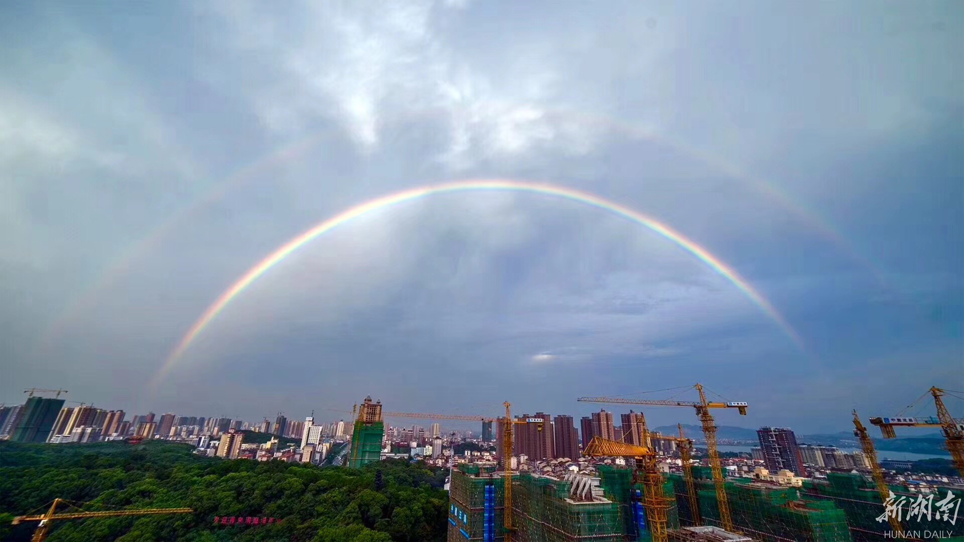 当天,岳阳天气闷热,天空风云变幻,雨滴时不时飘落,天边出了彩虹,而且