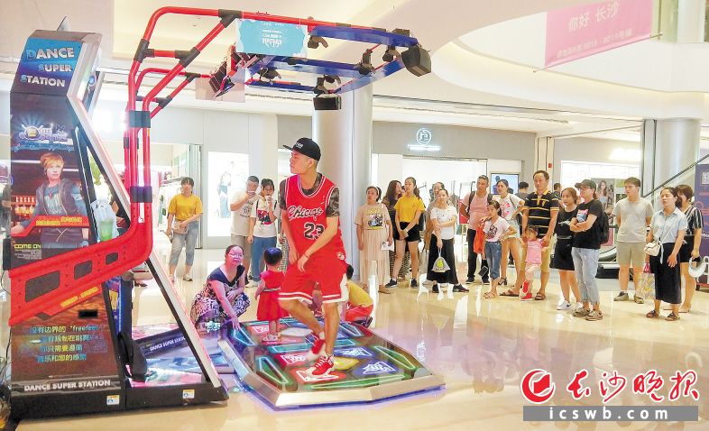 跳舞机上活跃的帅哥萌娃，成为国金街逛街人群的目光聚焦点。长沙晚报记者 王斌 摄