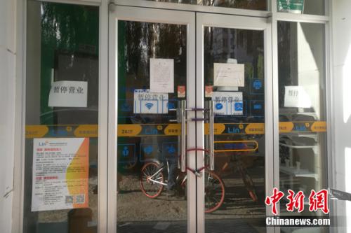 北京街边的某邻家便利店大门紧锁，并张贴着暂停营运的公告。