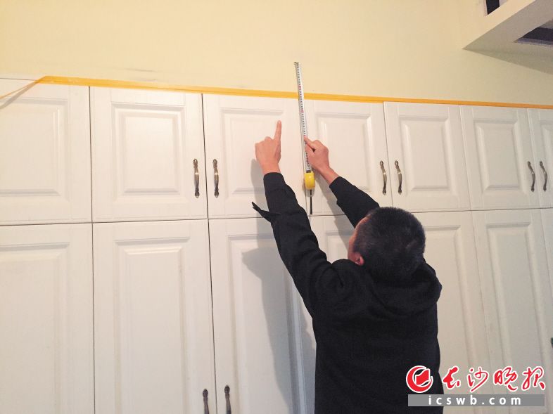 衣柜与房梁底部（卷尺头部）有12厘米悬空，装修公司为赶工期只得用石膏板、木板进行封闭。均为长沙晚报记者 朱炎皇 摄