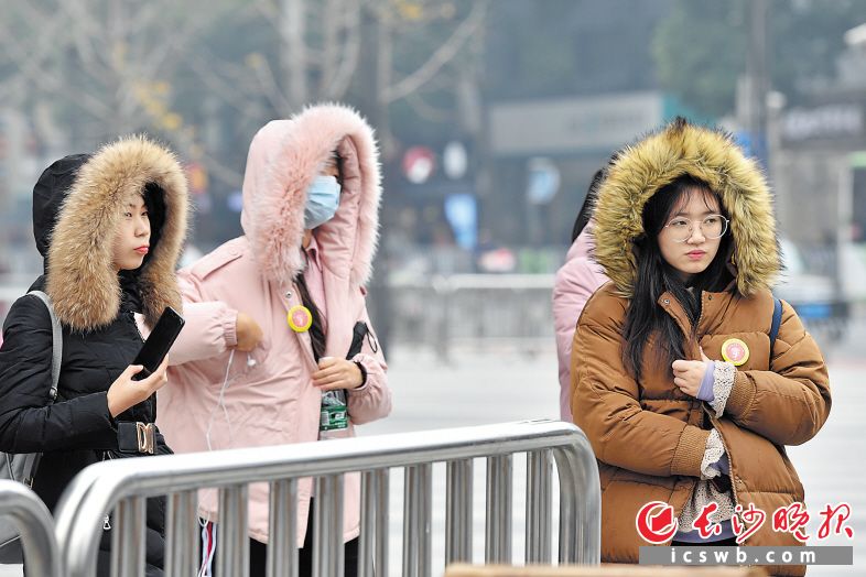 昨日下午，长沙国金中心附近，过往市民“全副武装”应对降温。 长沙晚报记者 王志伟 摄