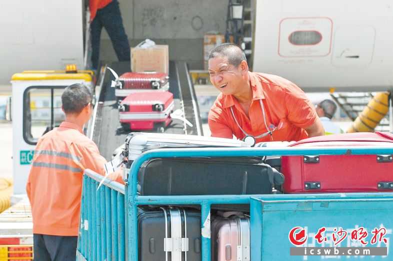 搬运装卸员吴金祥正在搬运大件行李，他的额头沁出了汗珠。 均为长沙晚报全媒体记者 王志伟 摄