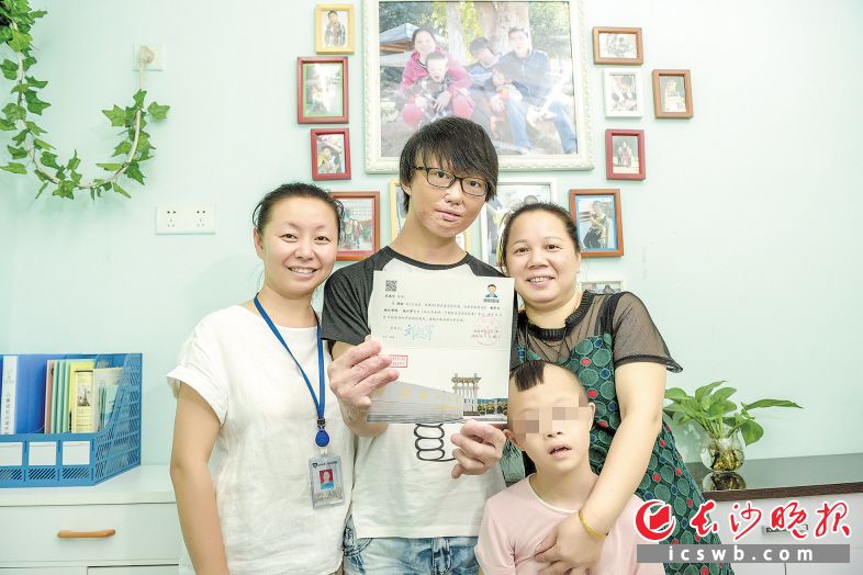 福利院的类家庭出了个大学生,范鸿宇(左二)和“妈妈”“弟弟”以及福利院工作人员合影。长沙晚报全媒体记者 陈飞 摄