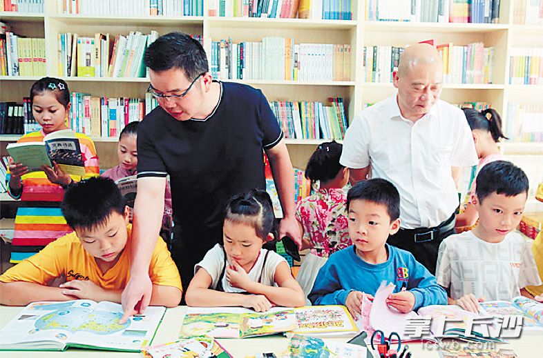 胡健老师(戴眼镜者)在公益书屋给孩子们解疑释惑。受访者供图