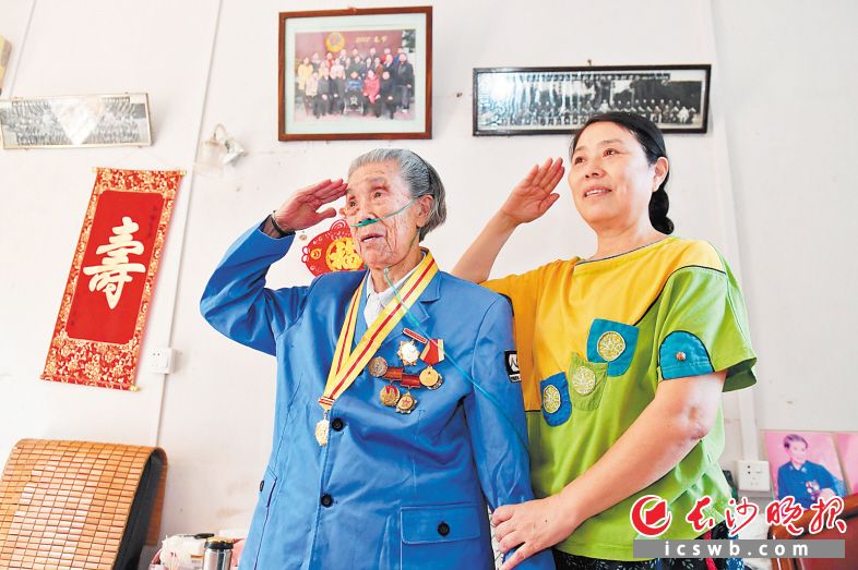 阅兵式进行中，余新华（左）和女儿对着电视机屏幕敬了个军礼。长沙晚报全媒体记者 王志伟 摄