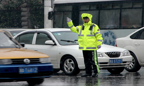 長沙市八一路與韶山路交叉路口,交警譚海穿著新式雨衣在雨中執勤