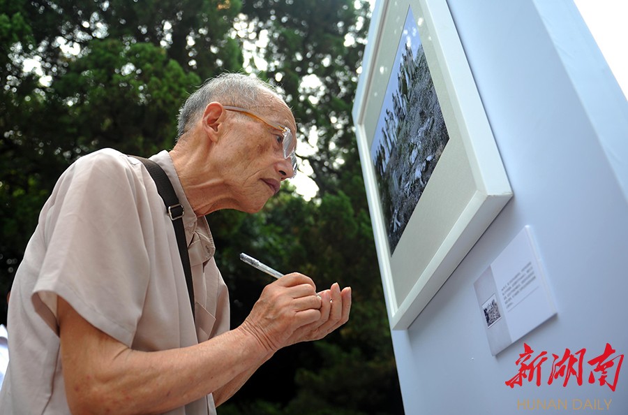 9月2日,8旬老人郑兆龙一边观看图片展,一边认真做笔记.