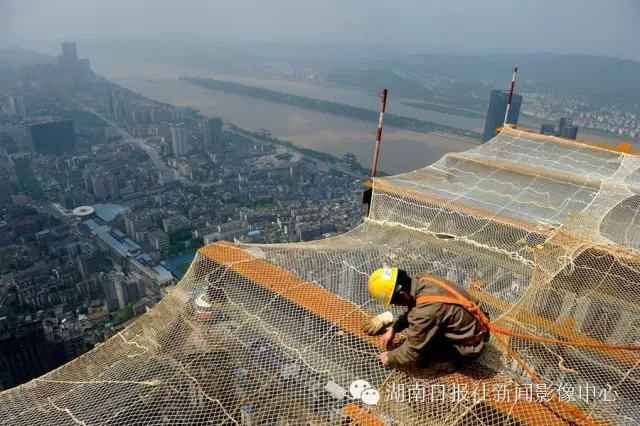 一名安全员在钢梁上安装安全防护网,以保障施工人员的安全.