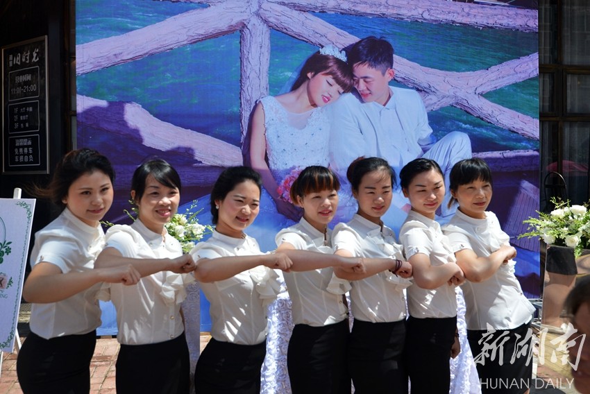 饭馆服务员在刘双田和唐娅萍的海报前合影