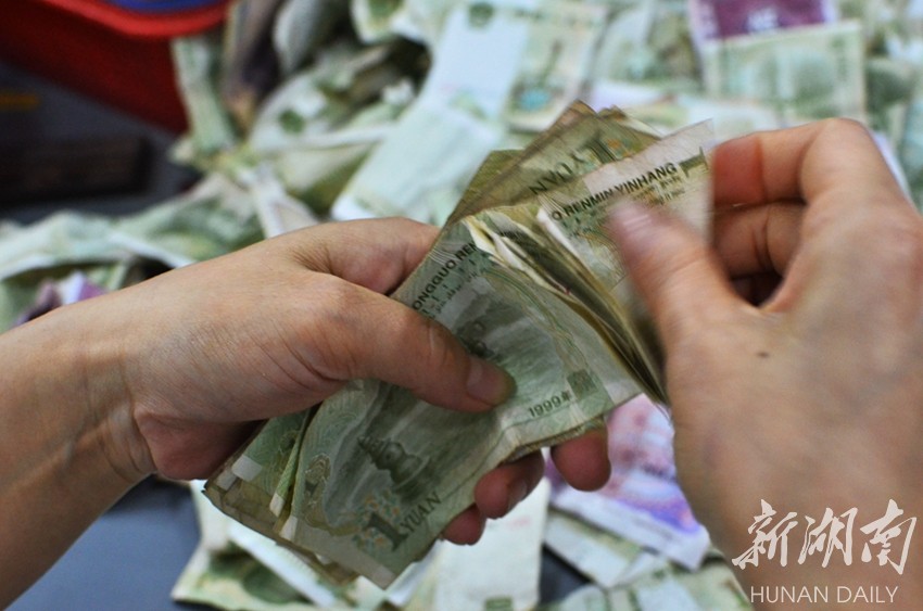 点钞员骆小艳将钱箱内胆的零钱小心翼翼地倾倒在桌面上.