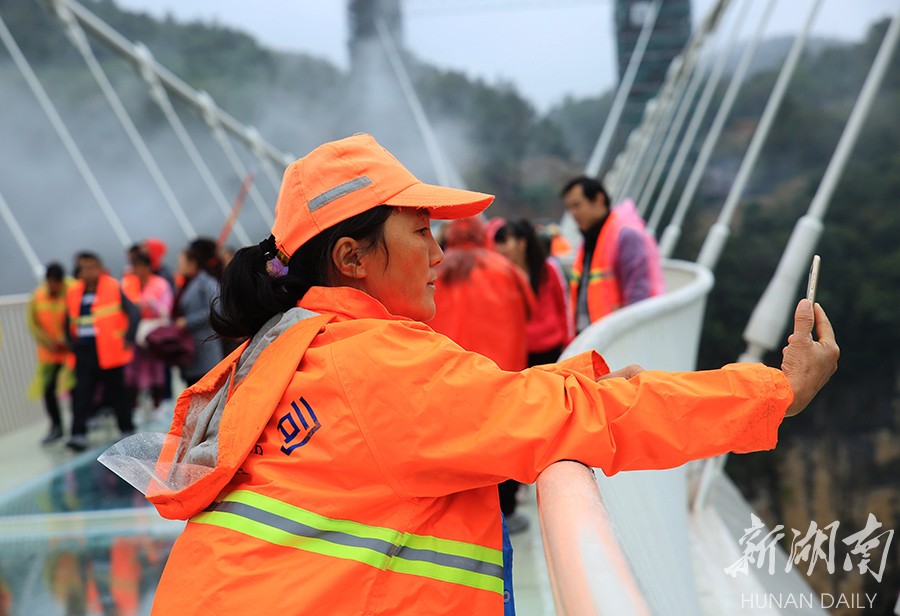 10月26日,一名环卫工人在张家界大峡谷玻璃桥上玩自拍.