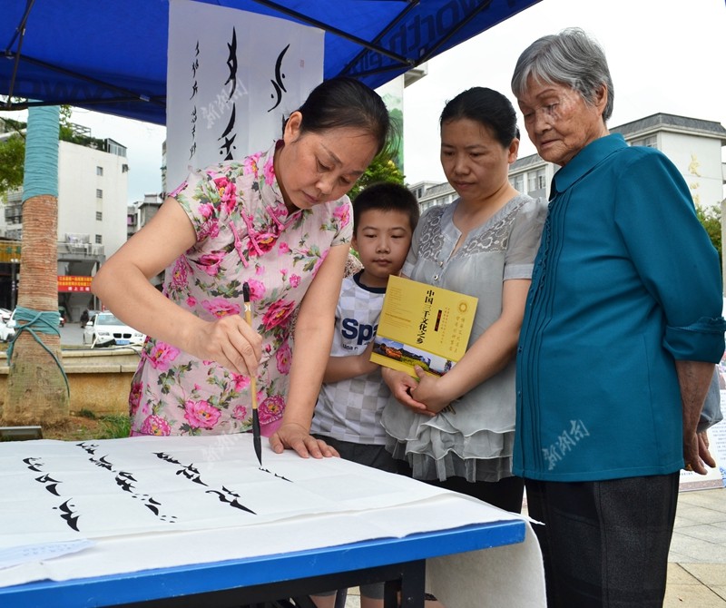 6月10日,江永县知青广场,女书传人蒲丽娟在为市民挥毫书写世界