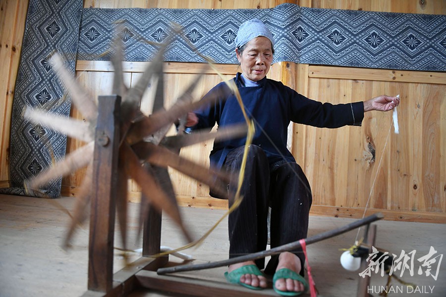 一位70多岁的侗族妇女在用传统的纺纱机制作纱线.