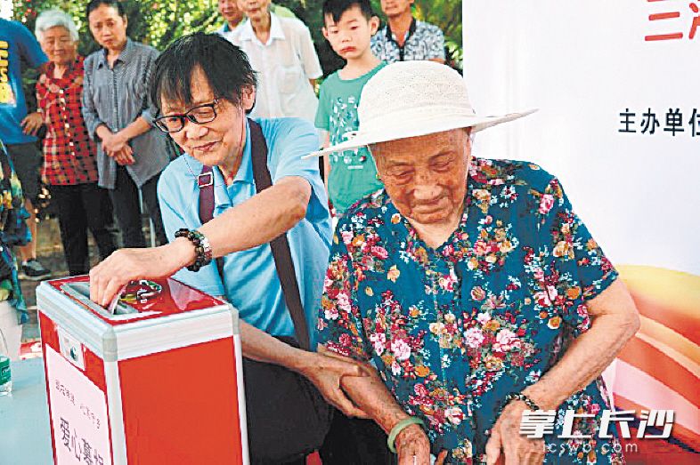 颜腾芳娭毑(右一)与女儿颜业珍在社区进行爱心捐款.