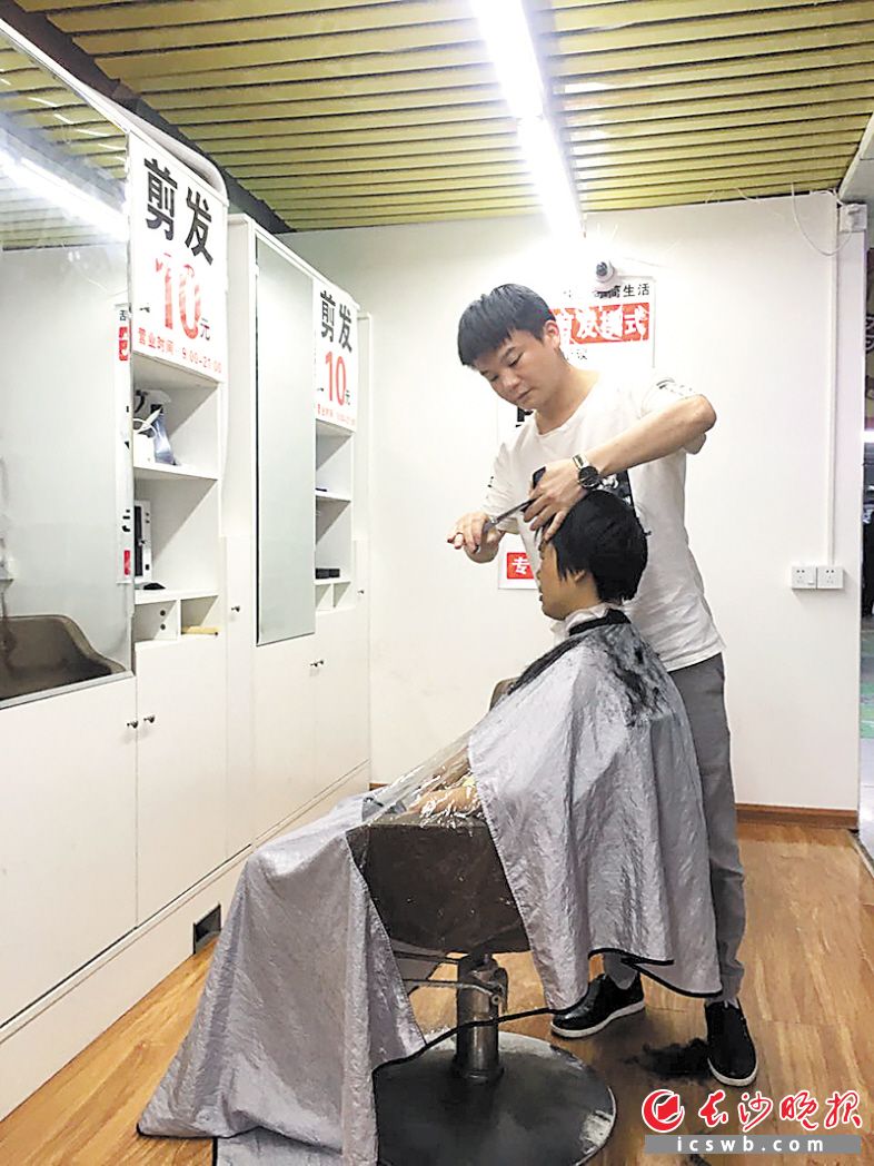 无论男女老幼剪个头只要10元钱10分钟,图为理发师正在为顾客剪头发