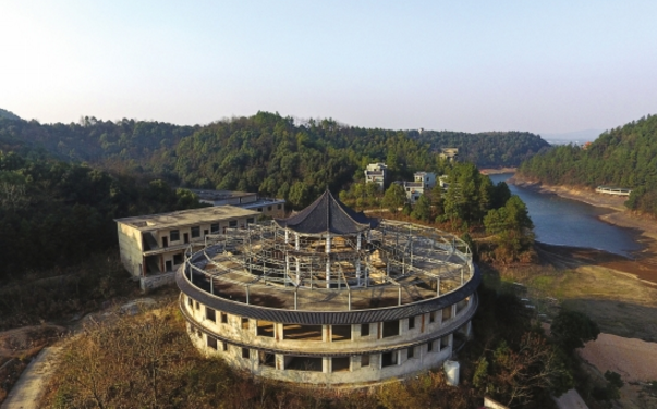 12月19日,湘潭市雨湖区海龙山庄,未完成的建筑旁杂草丛生.