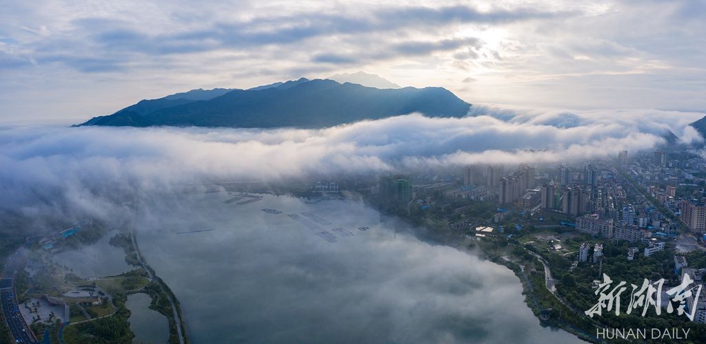 7月15日,湖南郴州资兴东江湾瀑布周围云雾缭绕,建筑与江湾在雾中若